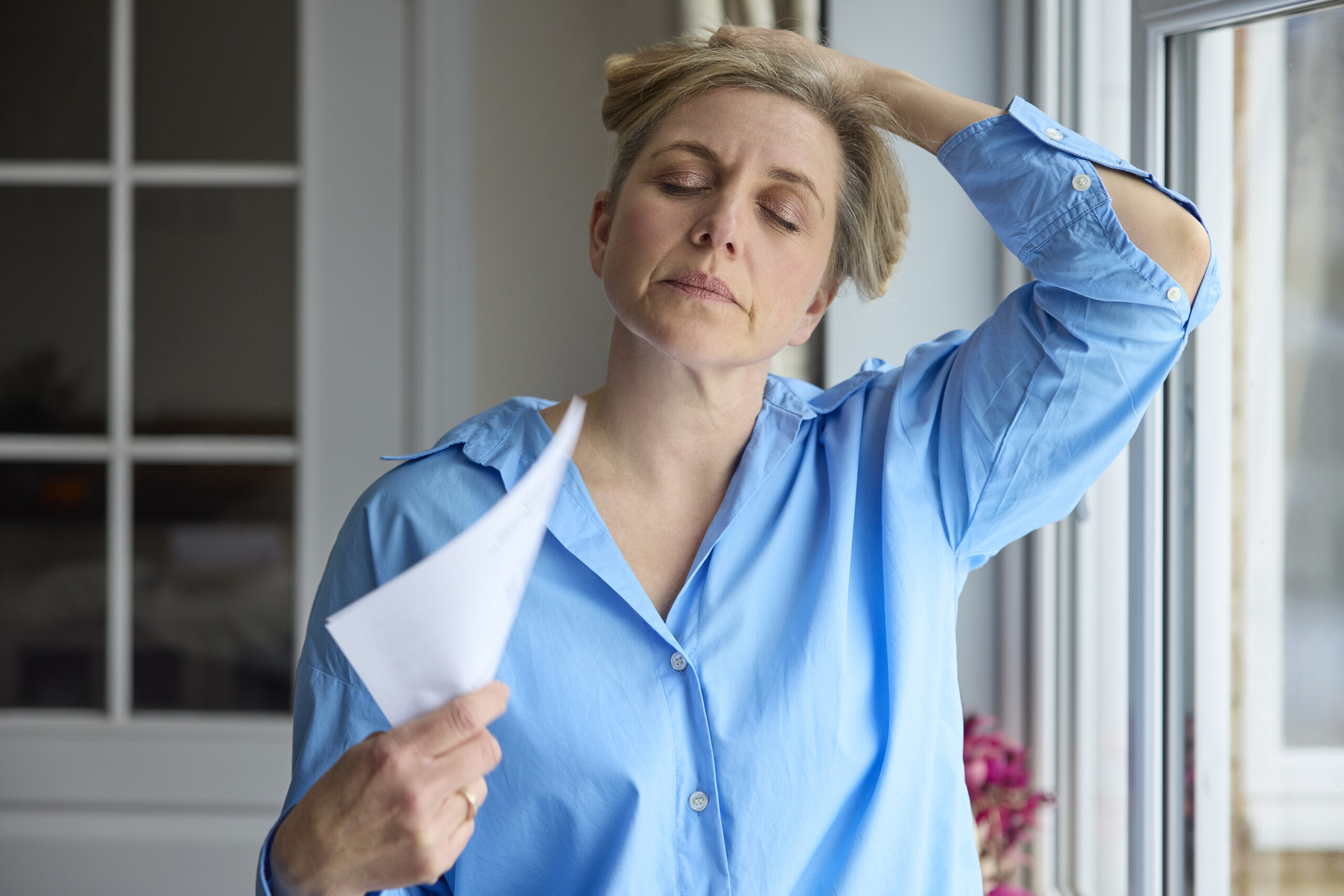 Woman experiencing hot flashes during menopause and fanning herself to keep cool and find relief