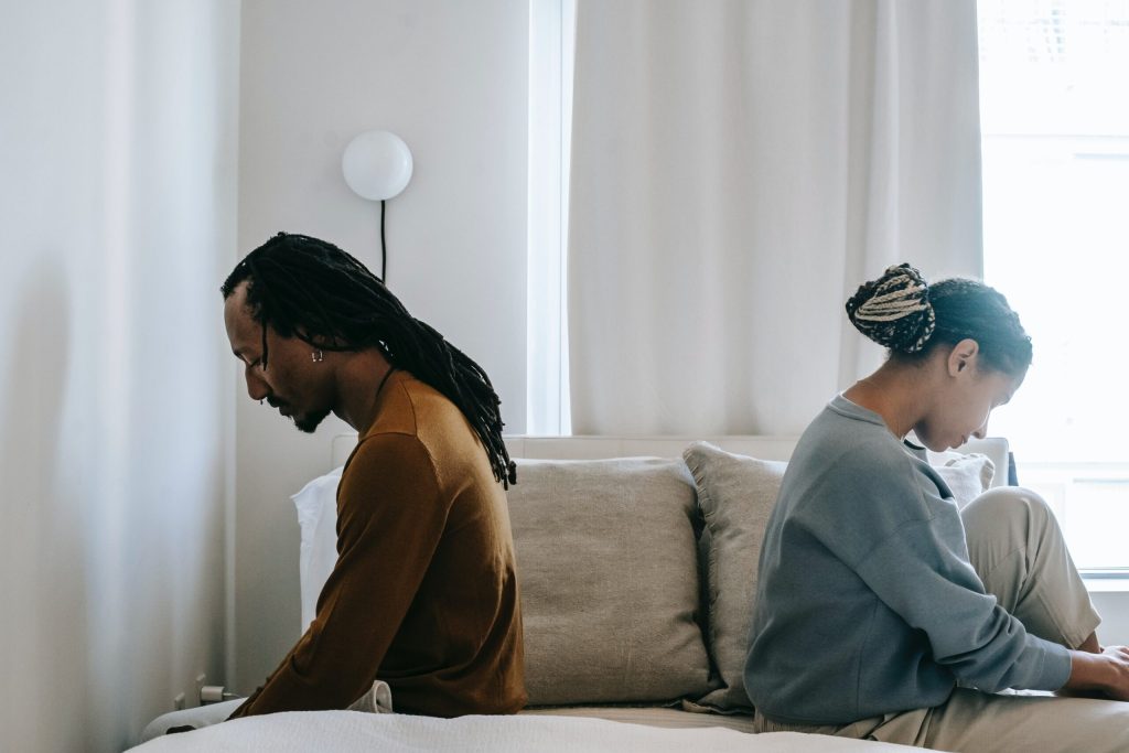 Couple in bedroom looking upset and disappointed