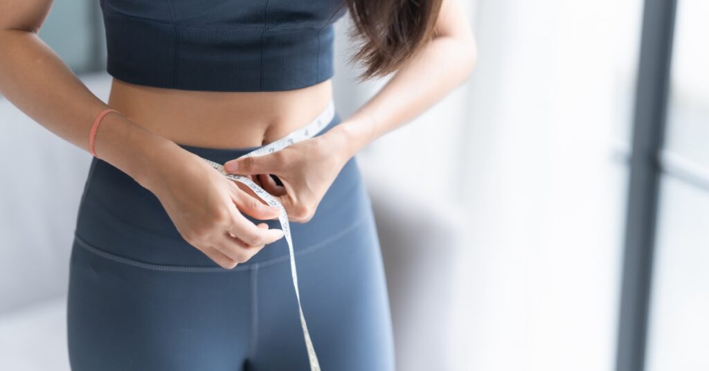 Woman checking her weight on a scale while tracking progress during weight loss treatment
