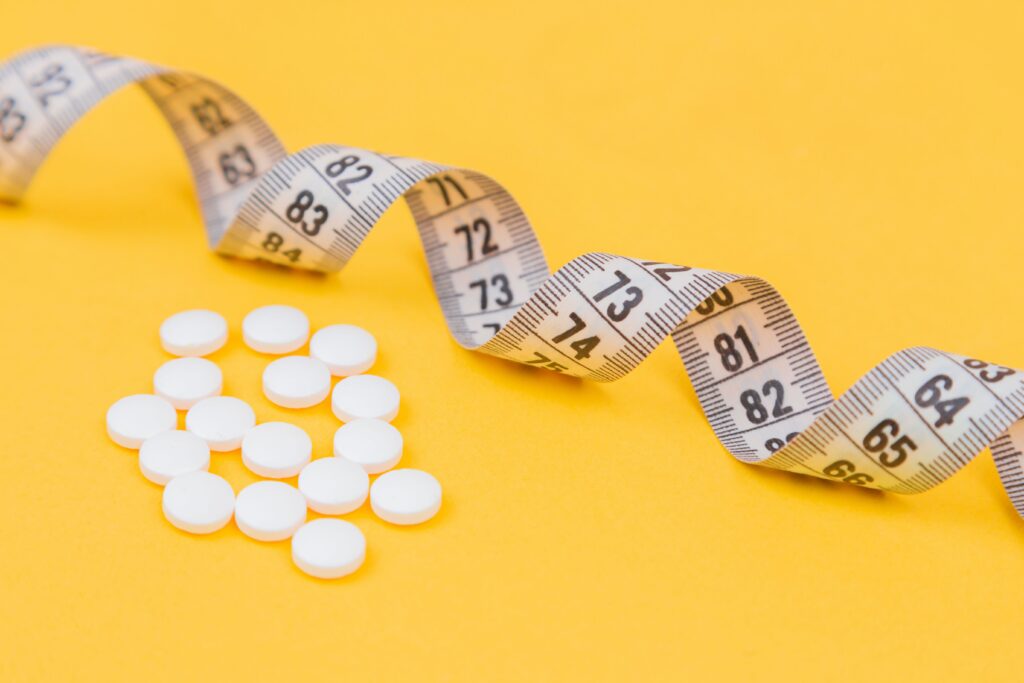 Tirzepatide and Semaglutide pills next to a body tape
