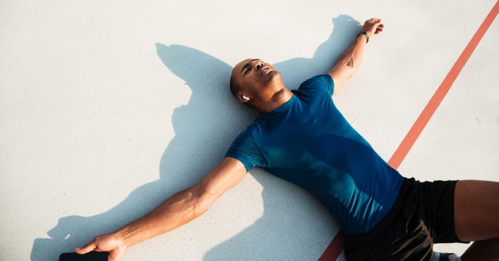 Man experiencing fatigue during exercise, lying down to recover between sets