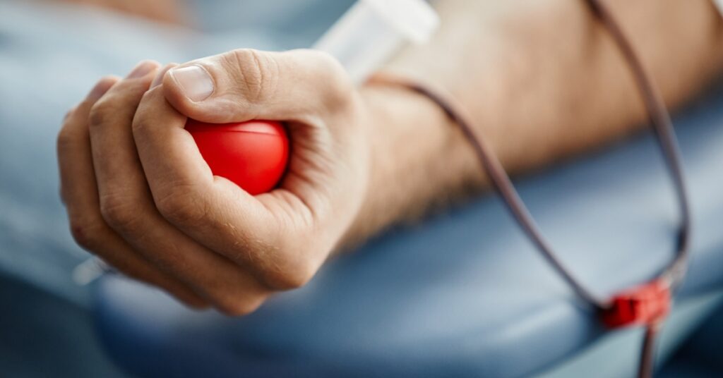 Man squeezing a stress ball while getting blood drawn