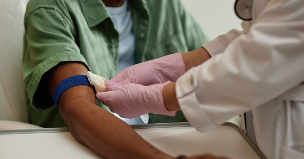 Man sitting in a clinic chair preparing for a blood draw to monitor hormone levels during TRT