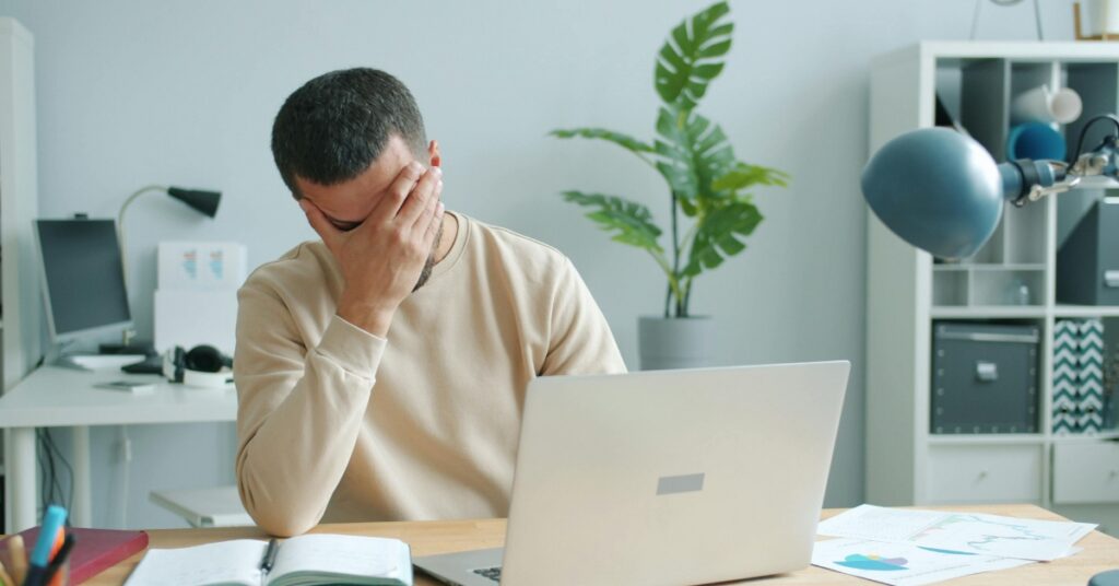 Man struggling with brain fog and concentration while working on a laptop