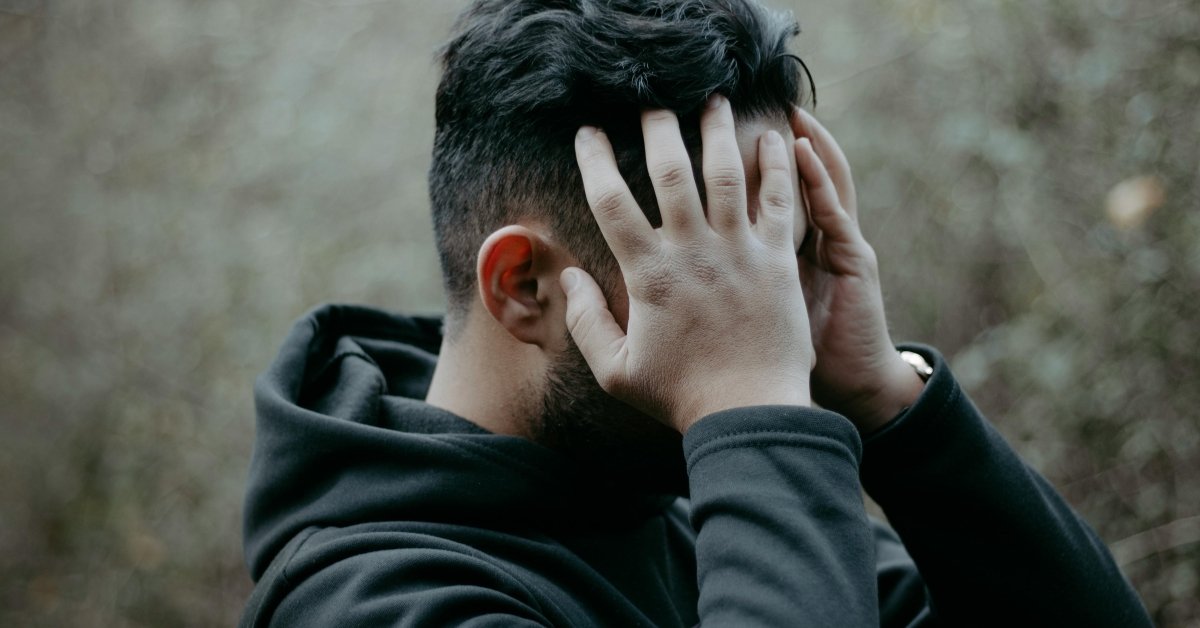 Man experiencing brain fog and mental fatigue while holding his head