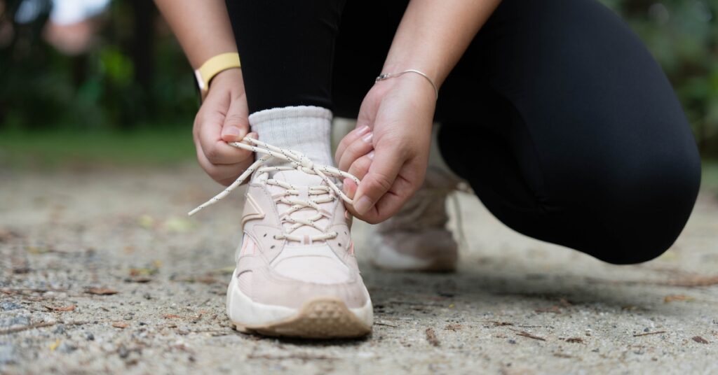 Woman tying her athletic shoes before a workout, representing healthy lifestyle habits during weight management treatment