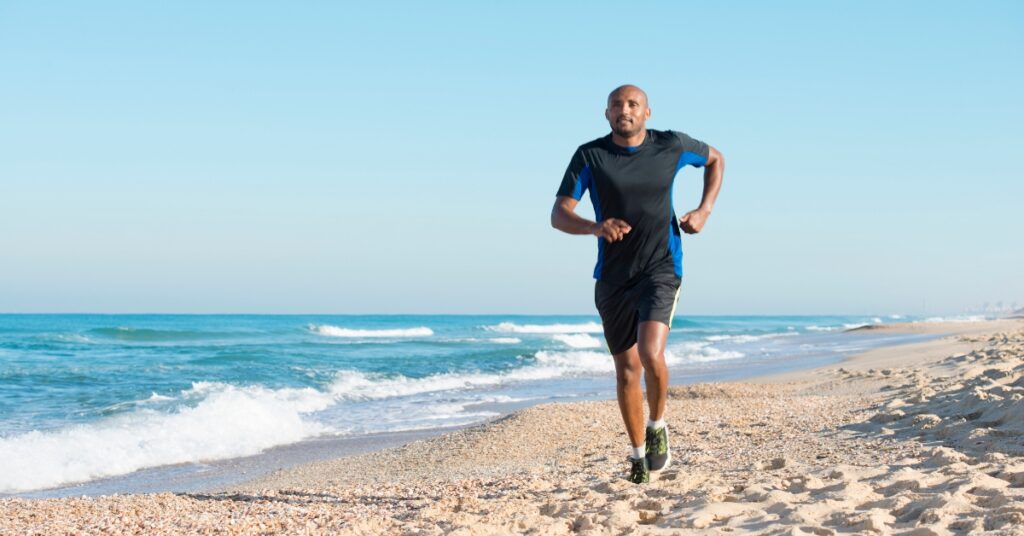 Man running along the beach at sunrise, representing energy, vitality, and overall wellness