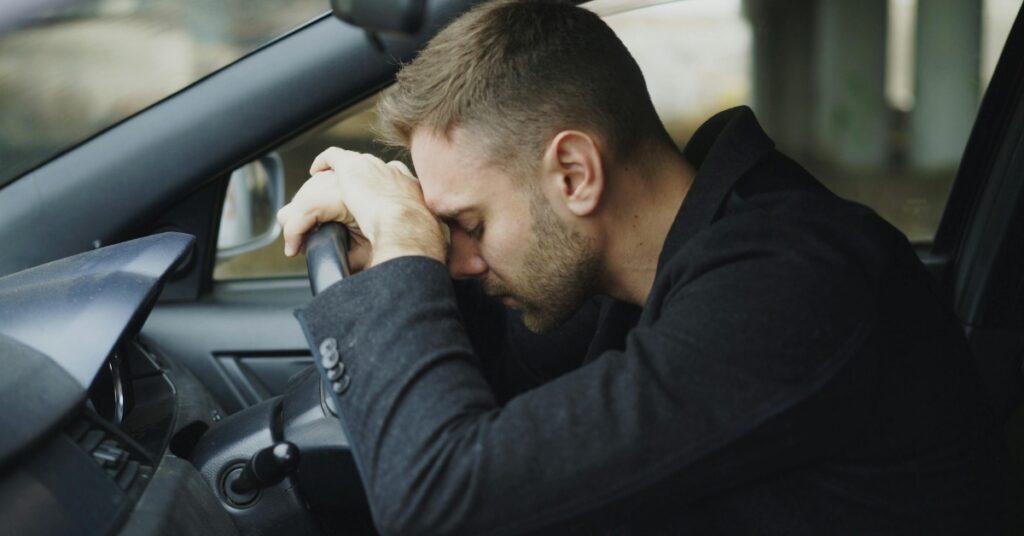 Man feeling fatigued and emotionally drained while sitting in his car