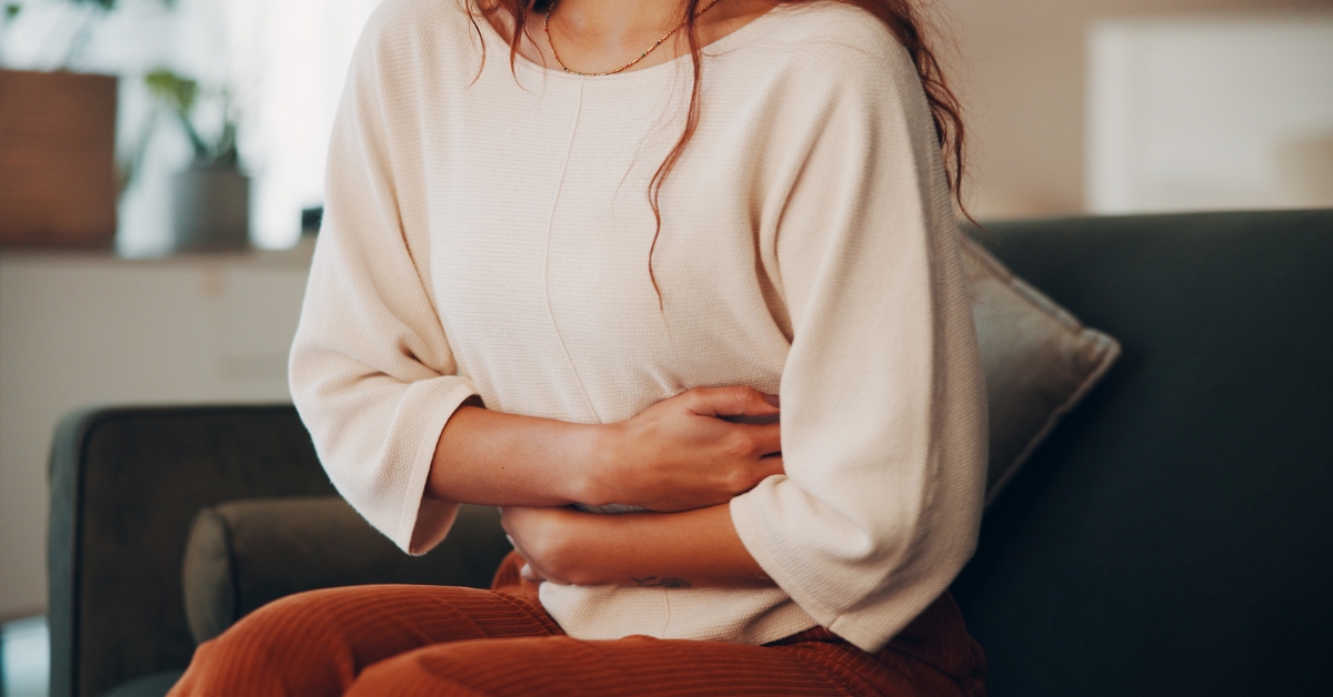 Woman holding her stomach while experiencing bloating during menopause