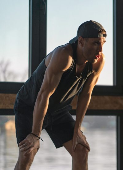 Young man is standing leaned on his knees and taking a breath after exercising in the gym.
