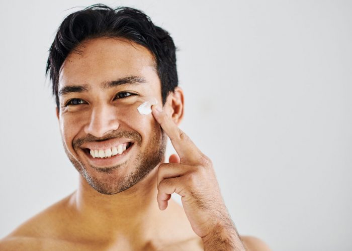 Skincare, healthy skin and selfcare routine using moisturizer to achieve a clean and flawless complexion. Handsome and happy male using cream to hydrate and protect while practicing good hygiene