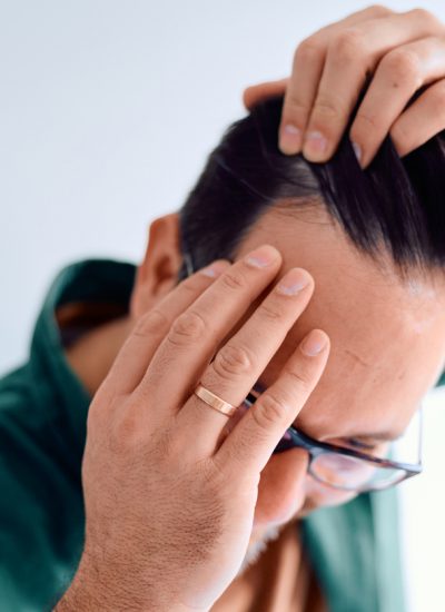 Middle-aged man examining his receding hairline in a mirror, worried and stressed about thinning hair and early male pattern baldness, close-up profile showing concern and self-care inspection