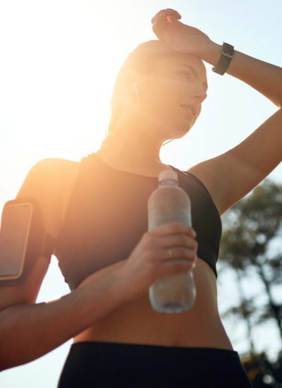 Shot of a fit young woman stopping for a drink of water during a run outdoors